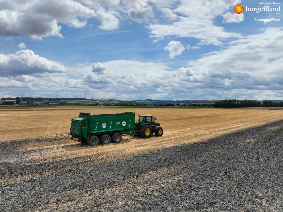 Traktor mit Gülleanhänger düngt Feld in Österreich, Windräder im Hintergrund