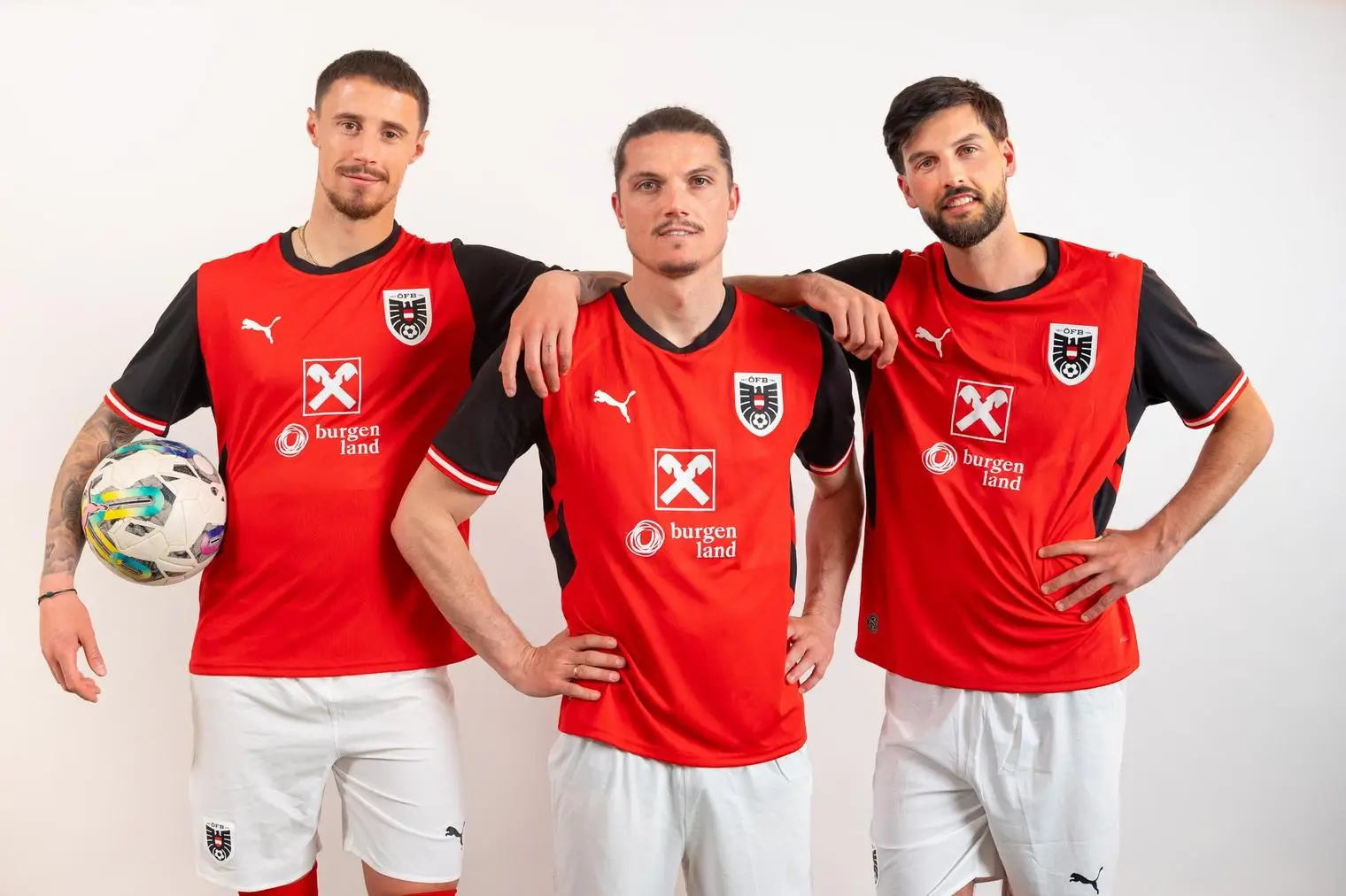 Fußballspieler des österreichischen Nationalteams in roten Trikots mit ihren Händen auf den Schultern ihrer Kollegen